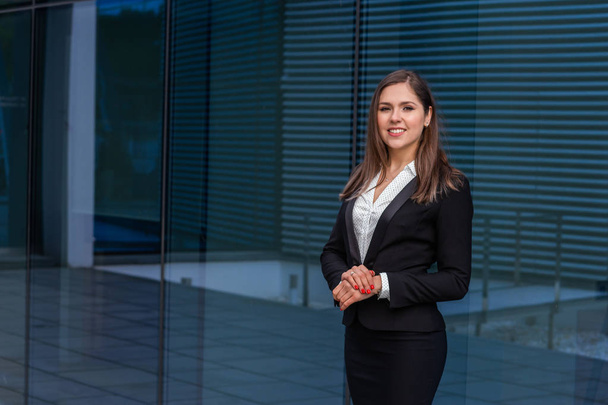 Confident businesswoman in front of modern office building. Business, banking, corporation, real estate and financial market concept. - Photo, image
