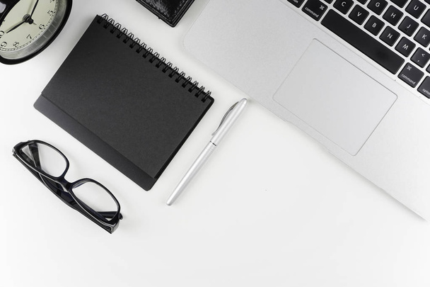 pracovní stůl s brýlemi, učebnicem papíru a perem na bílém povrchu s časem laptopu a budíku  - Fotografie, Obrázek