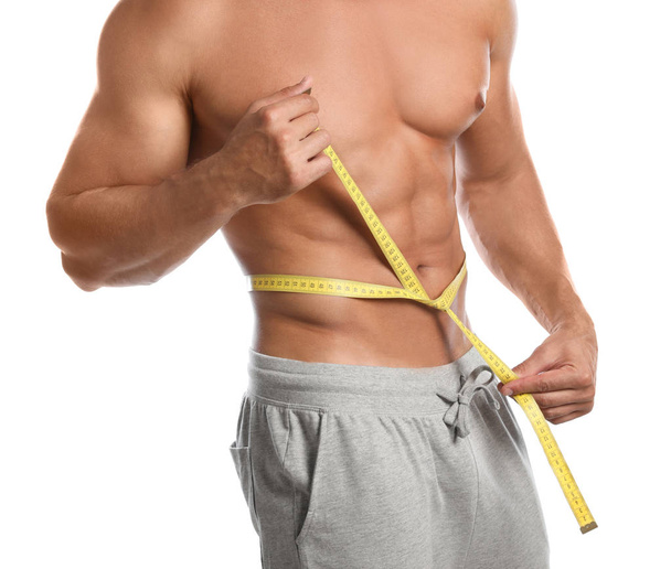 Young man with slim body using measuring tape on white background, closeup view - Photo, Image