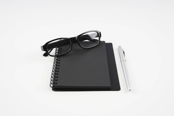 eyeglasses, paper textbook and pen on white surface   - 写真・画像