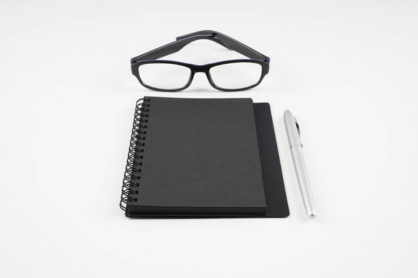 eyeglasses, paper textbook and pen on white surface   - Fotografie, Obrázek