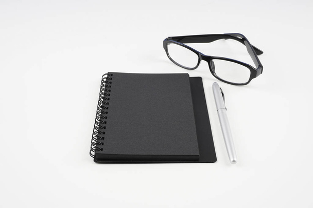 eyeglasses, paper textbook and pen on white surface   - Fotografie, Obrázek