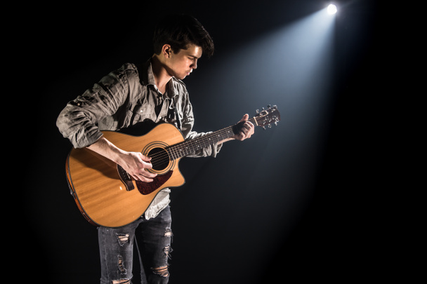 Guitarrista, música. Un joven toca una guitarra acústica en un blac
 - Foto, Imagen