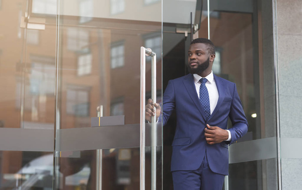Itsevarma afrikkalainen liikemies kävelee ulos nykyaikaisesta toimistokeskuksesta
 - Valokuva, kuva