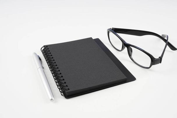 eyeglasses, paper textbook and pen on white surface   - Photo, Image