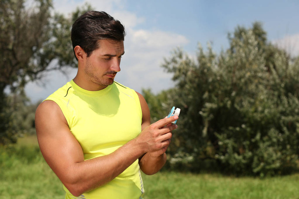 Young man checking pulse with medical device after training in park. Space for text - Fotoğraf, Görsel