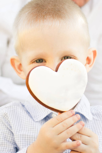 Ritratto di un ragazzo che tiene un biscotto a forma di cuore su un bastone
 - Foto, immagini