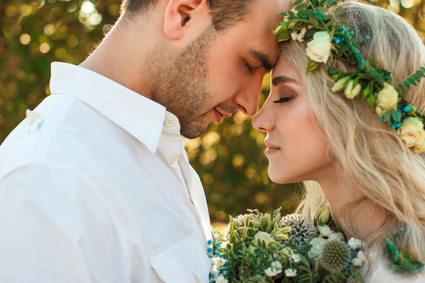 Bride in white dress and wreath and groom portrait in sunny summer day. Rustic outdoor wedding concept. Soft selective focus. - Fotografie, Obrázek