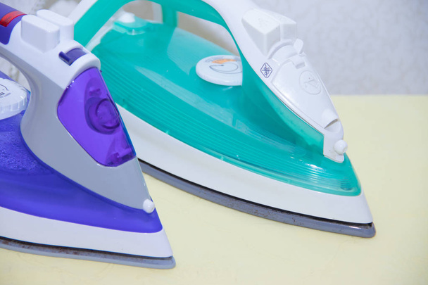Two irons on an ironing board. Selection and comparison of irons. Ironing board. - Photo, Image