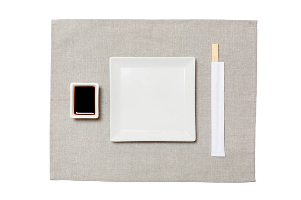 Üres fehér négyzetlemez a pálcika a sushi és a szójaszósz a szürke szalvéta háttérben. Felülnézet másolási területtel a tervezéshez - Fotó, kép