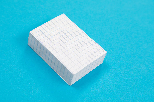 Stos białego papieru zdrapkowego leży na platformie Azure powierzchni na białym tle - Zdjęcie, obraz