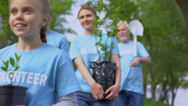 Eco volunteers walking park holding plant saplings shovel, nature conservation - Footage, Video