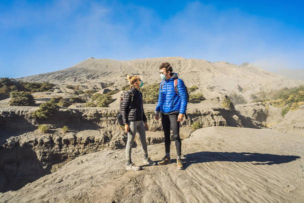 Young couple man and woman visit the Bromo volcano at the Tengger Semeru National Park on Java Island, Indonesia. They enjoy the magnificent view on the Bromo or Gunung Bromo on Indonesian, Semeru and - Zdjęcie, obraz