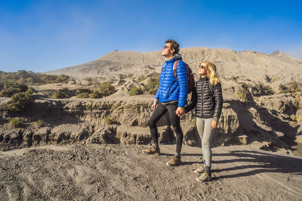 Young couple man and woman visit the Bromo volcano at the Tengger Semeru National Park on the Java Island, Indonesia. They enjoy magnificent view on the Bromo or Gunung Bromo on Indonesian, Semeru and - Foto, Imagen
