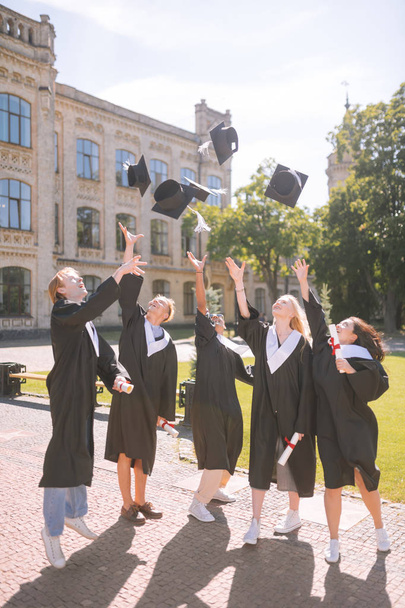 Graduating students throwing their masters caps up. - Фото, изображение