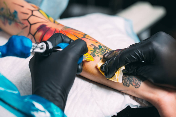 Professional tattoo artist makes a tattoo on a young girls hand. - Foto, afbeelding