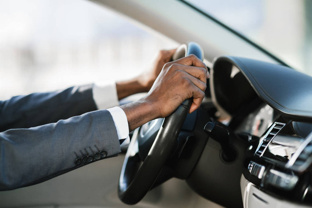 Бізнесмен водить машину на шосе, тримаючи руки на колесі
 - Фото, зображення