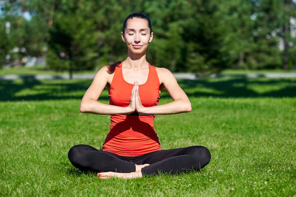 Yoga. Young woman practicing yoga meditation in nature a park. l - Фото, изображение