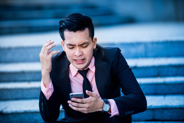 Стрессовый и злой азиатский бизнесмен смотрит на смартфон scre
 - Фото, изображение