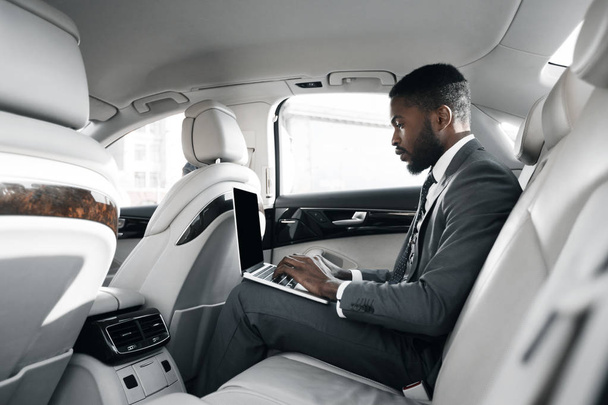 African-american businessman working on laptop in car - Foto, imagen