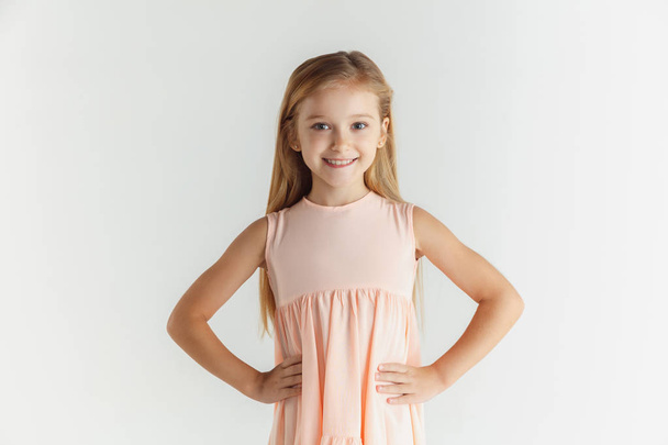 Little smiling girl posing in dress on white studio background - Foto, afbeelding