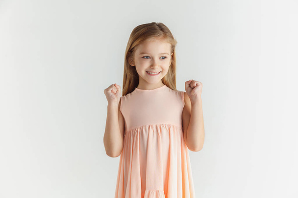 Little smiling girl posing in dress on white studio background - Foto, imagen