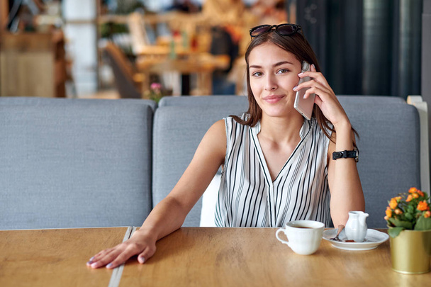 Young business woman talking on the phone in coffee shop - Foto, imagen