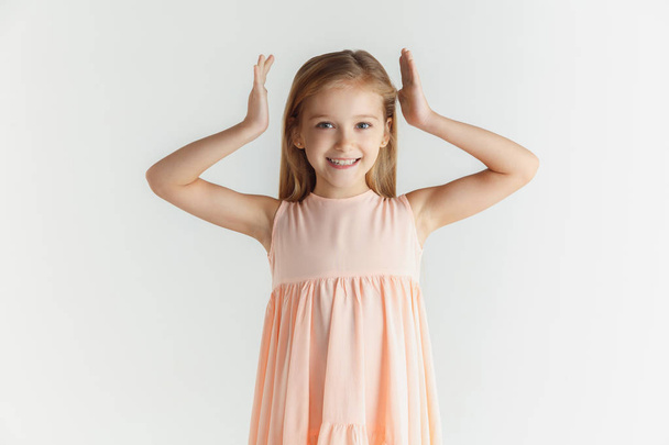 Little smiling girl posing in dress on white studio background - Foto, Imagen