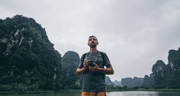 Valkoihoinen mies näköalalla kalkkikiveä vuorille Ninh Binh maakunnassa, Vietnamissa. Pilvinen päivä
 - Valokuva, kuva