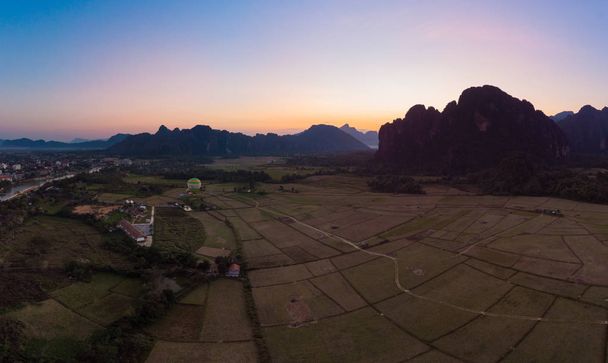 Aérienne : Vang Vieng Backpacker Voyage destination au Laos, Asie. Coucher de soleil sur les falaises pittoresques et les pinacles rocheux, vallée des rizières, paysage magnifique
. - Photo, image