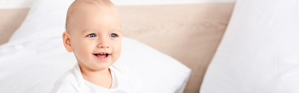 Panoramic shot of cute little child with blue eyes smiling in white room - Foto, Imagem