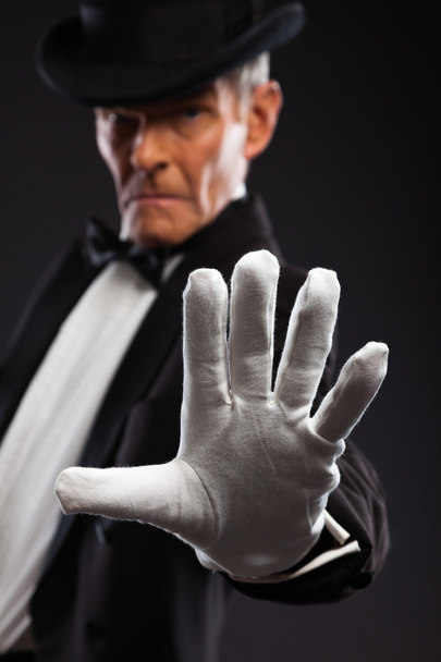 Magician making mysterious gestures. Wearing black suit and hat. - Photo, Image