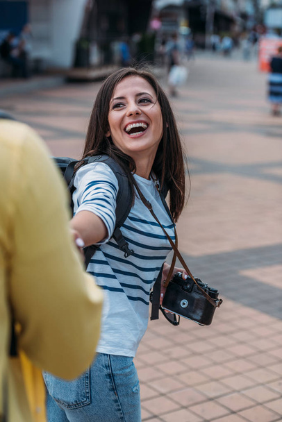 Female traveler with digital camera and backpack holding hand and smiling - Fotografie, Obrázek