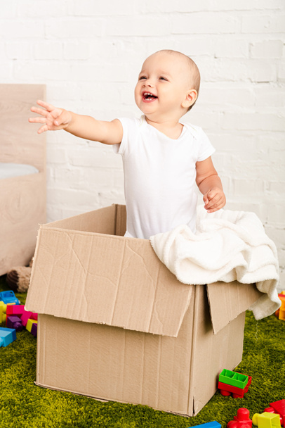 Happy little child standing in cardboard box and raising hand - Fotoğraf, Görsel