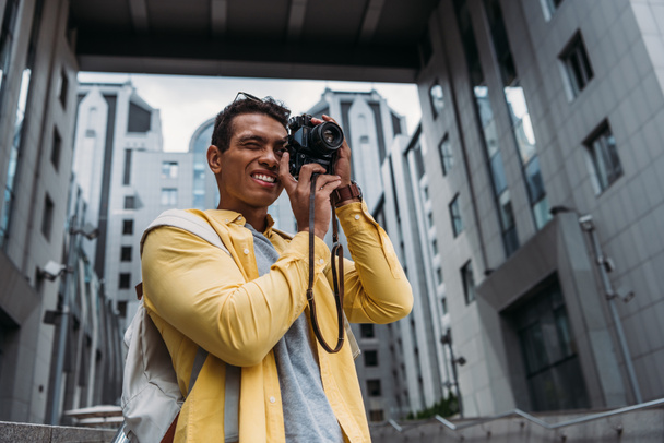 Bi-racial man taking photo on digital camera near buildings - Фото, изображение