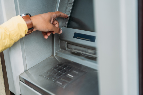 ATMマシン上のボタンを押す混合レースマンのトリミングビュー  - 写真・画像