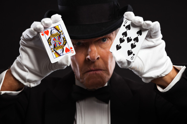 Magician with black suit and hat holding set of cards. Studio sh - Photo, Image