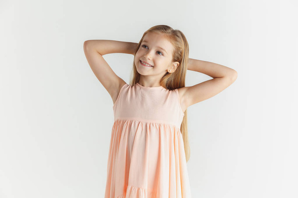 Little smiling girl posing in dress on white studio background - Foto, Imagem