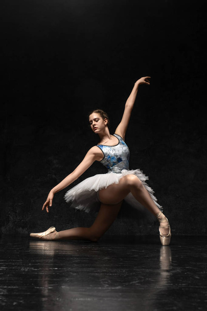 Ballerina. A young graceful ballerina dressed in professional attire, pointe shoes with ribbons and a white tutu, demonstrates dance skills. Beautiful classic ballet. Volumetric photos 3D. - Zdjęcie, obraz