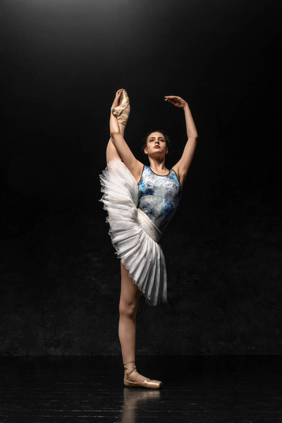 Ballerina. A young graceful ballerina dressed in professional attire, pointe shoes with ribbons and a white tutu, demonstrates dance skills. Beautiful classic ballet. Volumetric photos 3D. - Zdjęcie, obraz
