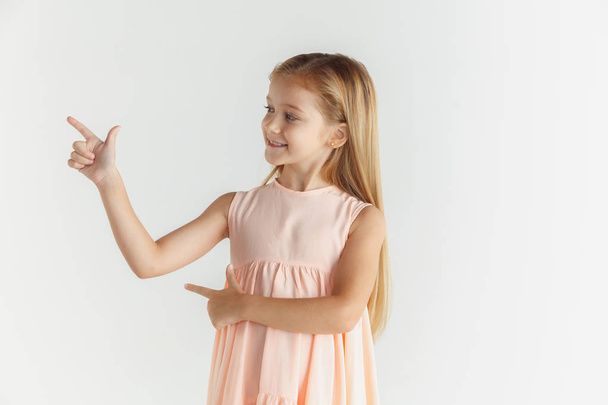 kleines lächelndes Mädchen posiert im Kleid auf weißem Studiohintergrund - Foto, Bild