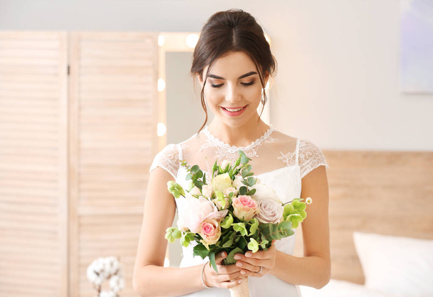 Beautiful young bride with bouquet of flowers at home - Photo, Image