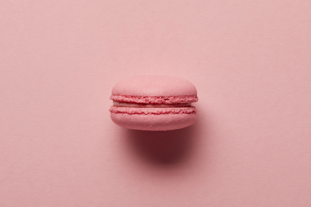 Pink french macaroon in center on pink background - Фото, изображение
