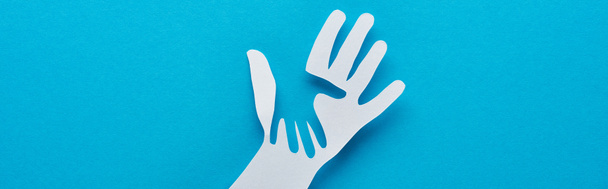 top view of paper cut parent and child hands on blue background, panoramic shot - Fotó, kép
