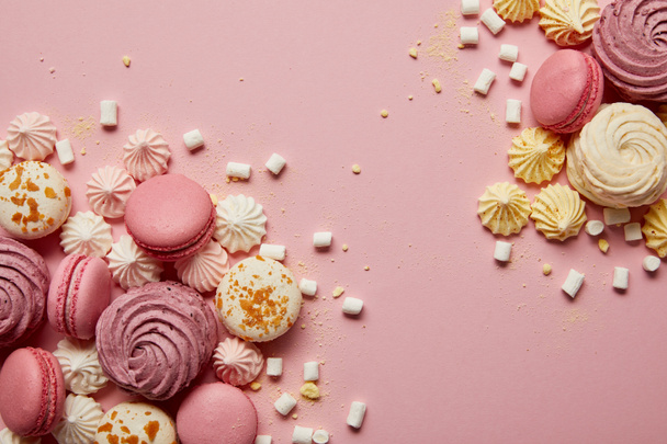 Top view herkullisia makeita makaroneja, marenkeja ja vaahtokarkkeja keltaisilla paloilla vaaleanpunaisella pohjalla
 - Valokuva, kuva