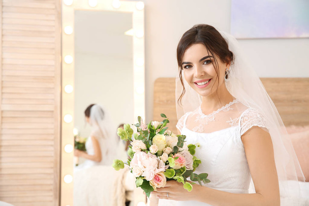 Beautiful young bride with bouquet of flowers at home - 写真・画像