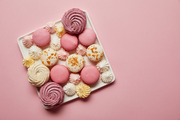 Vue de dessus des macarons et meringues français assortis sur plat carré sur fond rose
 - Photo, image