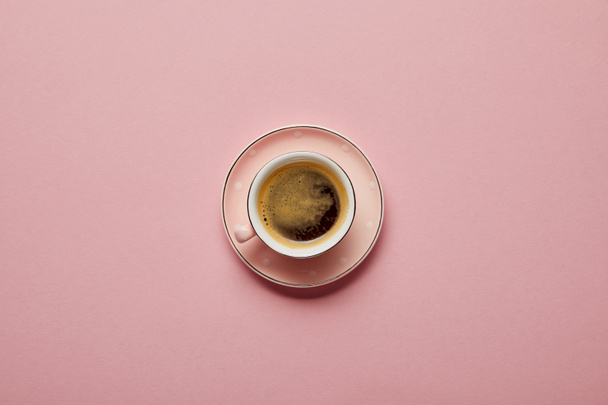 Cup of aromatic coffee at pink saucer with white dots on pink background - Photo, Image