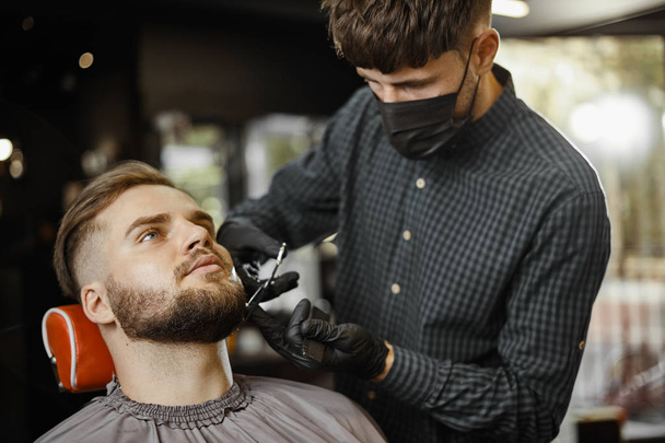 a guy doing a haircut and styling a beard  - Fotoğraf, Görsel