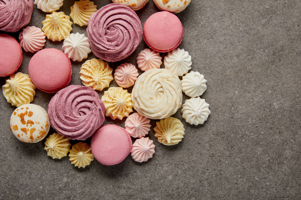 Top view of meringues, macaroons and fluffy white and pink zephyr on gray background - Valokuva, kuva